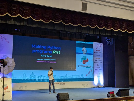 Kovid Goyal is giving keynote at PyCon India 2024 stage. His slide says "Making Python programs fast"